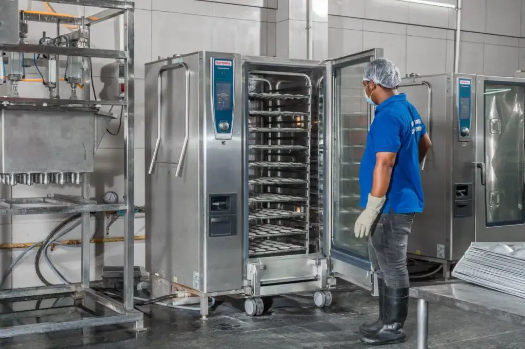 Chef inspecting commercial hygienic kitchen equipment in vegetarian catering unit in Bangalore